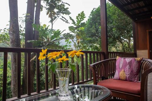 a vase of flowers on a table on a porch at De Serenity - Exclusive Jungle Retreat in Seremban