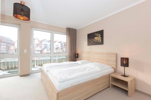 Schlafzimmer mit einem großen weißen Bett und großen Fenstern in der Unterkunft Marina 22-B in Cuxhaven