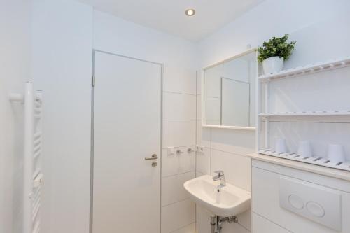 ein weißes Badezimmer mit einem Waschbecken und einem Spiegel in der Unterkunft Lord Nelson 212 in Döse