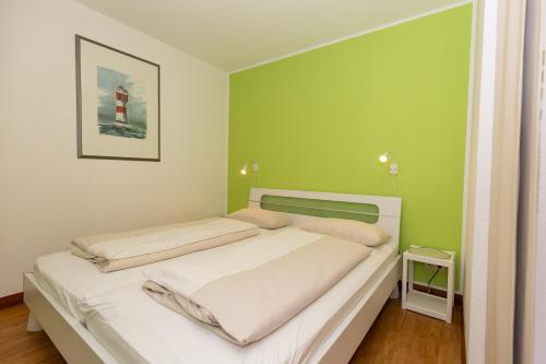 1 dormitorio con cama blanca y pared verde en Kurpark-Residenz 141 en Döse