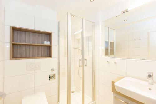 ein weißes Bad mit einer Dusche und einem Waschbecken in der Unterkunft Trafalgar 149 in Döse