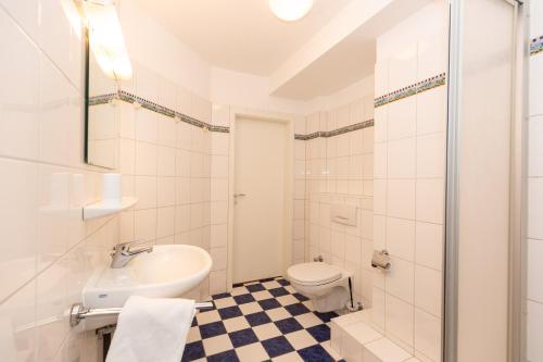ein weißes Bad mit einem WC und einem Waschbecken in der Unterkunft Kurpark-Residenz 242 in Döse