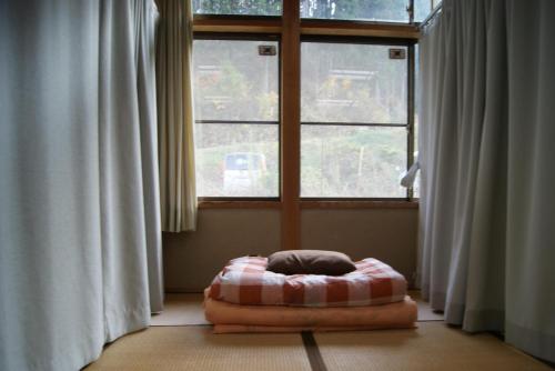 a room with a bed in front of a window at Awakura-onsen Motoyu in Nishiawakura