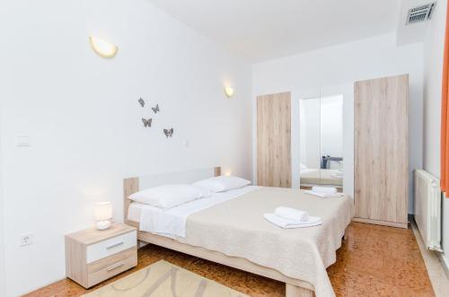 Un dormitorio blanco con una cama y un espejo. en Villa Ana, en Umljanović