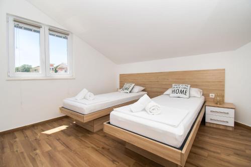 two beds in a room with white walls and wooden floors at Villa Divine in Vodice