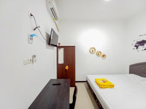 une chambre avec un lit et une table avec un objet jaune dans l'établissement Homestay Bahari near Wisata Bahari Tlocor Sidoarjo Mitra RedDoorz, à Bangil