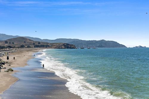 a beach with people walking on the sand and the water at @ Marbella Lane – Home with Majestic Ocean Views in Pacifica