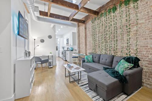 salon z kanapą i ceglaną ścianą w obiekcie Chic Industrial Home In City Center w mieście Hoboken