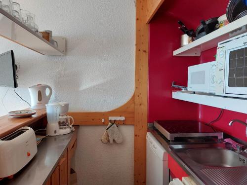 d'une cuisine avec des murs rouges, un évier et un comptoir. dans l'établissement Appartement cosy 6 pers, accès direct pistes et commerces, balcon sud, Arc 1800 Villards - FR-1-411-860, à Bourg-Saint-Maurice