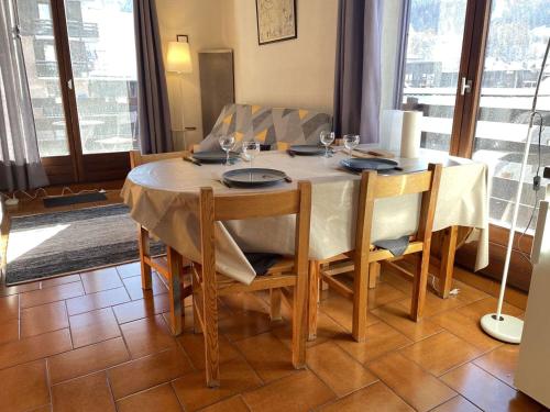 une table à manger avec des chaises et un tissu de table blanc dans l'établissement Appartement cosy à Risoul 1850, 3 pièces, 6 pers., pied des pistes, proche commodités et luge - FR-1-330-560, à Risoul