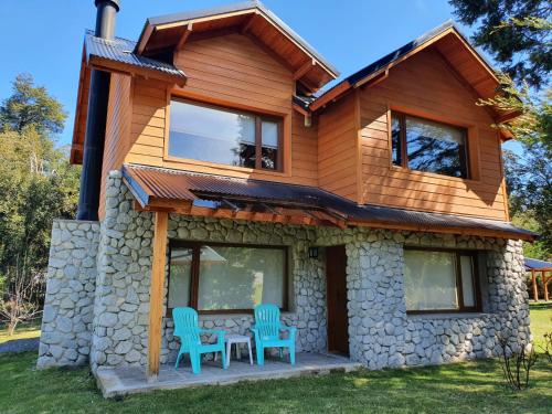a house with two chairs and a table in front of it at Encanto del Rio in Villa La Angostura