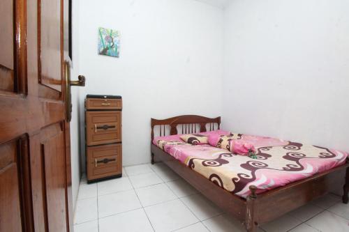 a small bedroom with a bed and a dresser at Kost&Guesthouse Tirza in Banyuwangi