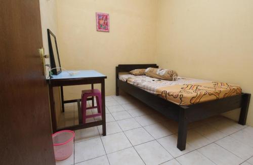 a small bedroom with a bed and a table at Kost&Guesthouse Tirza in Banyuwangi