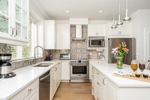 a kitchen with white cabinets and a vase of flowers at Comfortable and Modern Rowhouse Perfect for BC Escapade, air conditioned in Langley