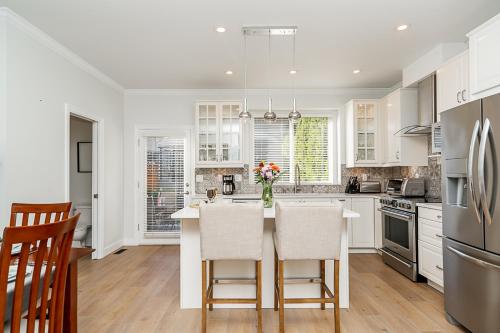 a kitchen with white cabinets and a table with chairs at Comfortable and Modern Rowhouse Perfect for BC Escapade, air conditioned in Langley