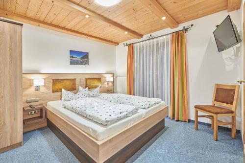 ein Schlafzimmer mit einem großen Bett und einem Stuhl in der Unterkunft Gästehaus Sonnenbichl in Berchtesgaden