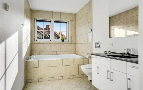y baño con bañera, aseo y lavamanos. en Cozy Apartment In Bogense With Sauna en Bogense