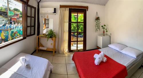 Un dormitorio con una cama con un animal de peluche en una manta roja en Rudá Hostel, en Itacaré
