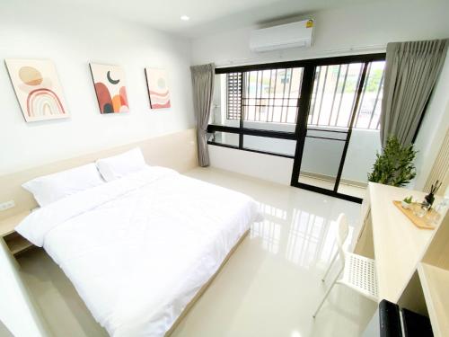 a white bedroom with a bed and a window at Rest Suvarnabhumi in Samutprakarn