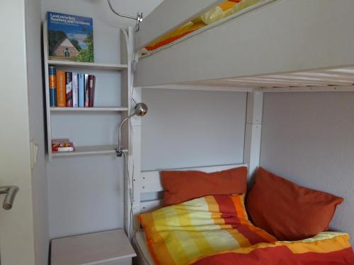 ein Schlafzimmer mit einem Etagenbett und einem Bücherregal in der Unterkunft Lord Nelson 214 in Döse