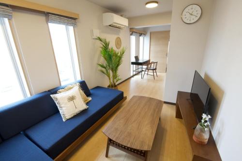 a living room with a blue couch and a table at メイスン倶楽部 501 in Asato