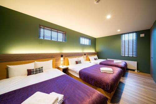 two beds in a room with green walls and windows at Sapporo - House - Vacation STAY 88283 in Sapporo
