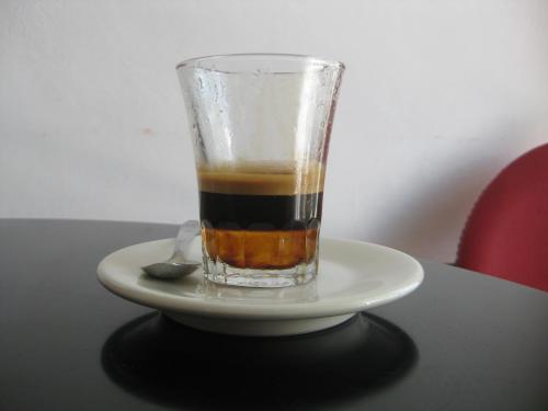 a cup of coffee on a plate on a table at Hotel Amelia in Fano
