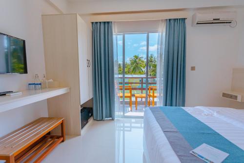 a hotel room with a bed and a balcony at Dhiguveli Breeze in Dhigurah