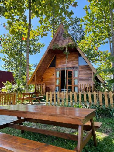 eine Blockhütte mit einem Picknicktisch davor in der Unterkunft Vila Glamping Lembah Kelud Kediri in Berni