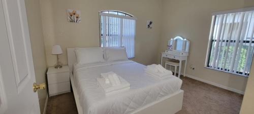 a small bedroom with a white bed and a mirror at Cheerful 4bed 3bath with pool home near Disney in Kissimmee
