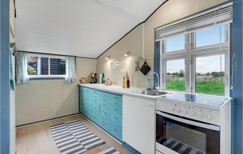 a kitchen with blue cabinets and a sink and a window at Pet Friendly Home In Nexø With Wifi in Neksø