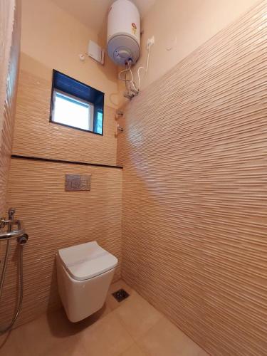 a bathroom with a toilet and a window at OmBodhi Retreat in Kumta