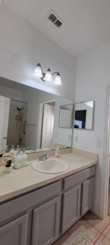 a bathroom with a sink and a large mirror at Cheerful 4bed 3bath with pool home near Disney in Kissimmee