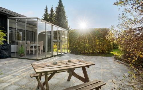 a wooden picnic table on a patio in front of a glass house at Awesome Home In Mern With Wifi in Mern