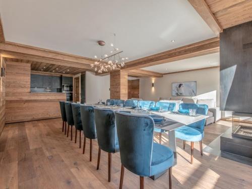 une salle à manger avec une grande table et des chaises bleues dans l'établissement Appartement de Luxe aux Allues : 5 Ch, Skis aux Pieds, Terrasses, Services Premium - FR-1-613-18, à Méribel