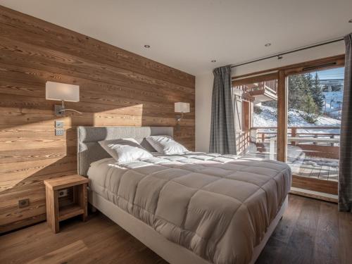 - une chambre avec un grand lit et un mur en bois dans l'établissement Appartement de Luxe aux Allues : 5 Ch, Skis aux Pieds, Terrasses, Services Premium - FR-1-613-18, à Méribel