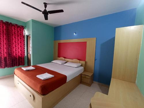 1 dormitorio con 1 cama con pared roja y azul en CASA FIESTA guest House en Palolem