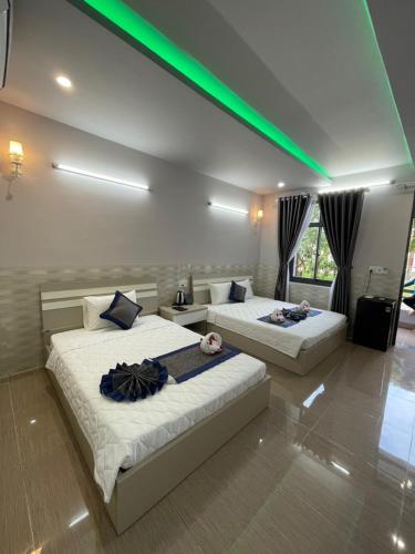 two beds in a room with green lights at Xuân Hải Complex-Hotel in Song Cau