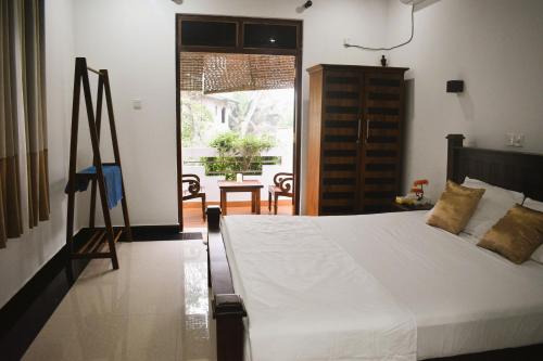 a bedroom with a white bed and a sliding glass door at Swarna's Place in Hikkaduwa