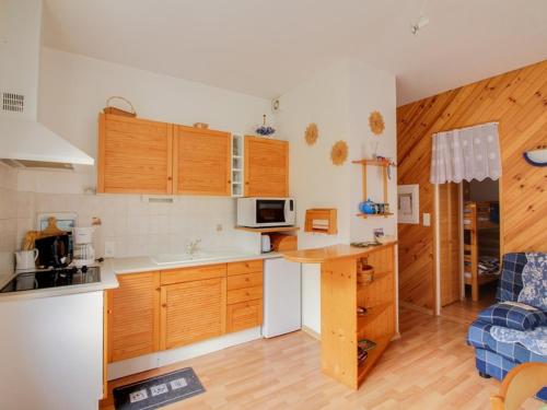 une cuisine avec des armoires en bois et un comptoir dans l'établissement Appartement T2 avec terrasse, coin nuit, parking et proximité télécabine - 4 pers. - FR-1-401-66, à Cauterets
