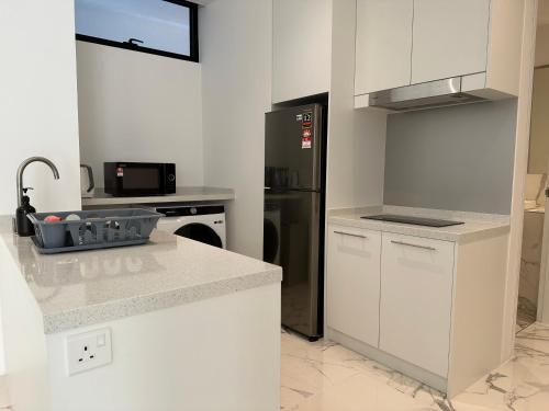 a kitchen with white cabinets and a stainless steel refrigerator at Lumi Tropicana in Petaling Jaya