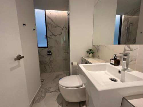 a white bathroom with a toilet and a sink at Lumi Tropicana in Petaling Jaya