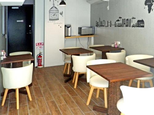 un restaurante con mesas de madera y sillas blancas en B&B Nagomi, en Tokio