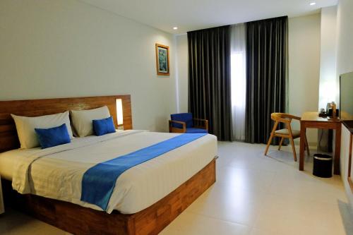 a bedroom with a large bed with blue pillows at Pollos Hotel & Gallery in Rembang