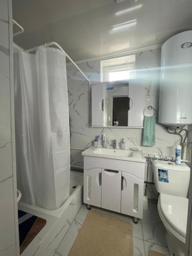 a white bathroom with a sink and a toilet at Guesthouse Gulmira in Bokonbayevo
