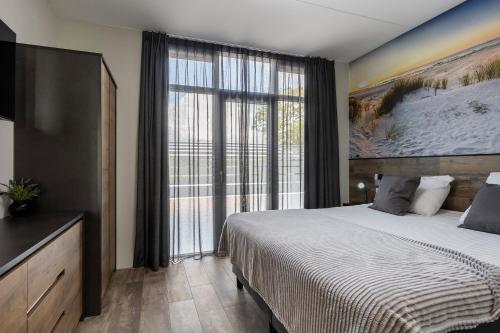a bedroom with a large bed and a large window at Holiday Apartment Strand in Noordwijk