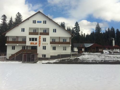 a large white building in the snow next to a field at Vila Sport Borsec in Borsec