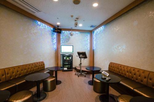 a room with chairs and tables and a television at KAMENOI HOTEL Kanonji in Kanonji