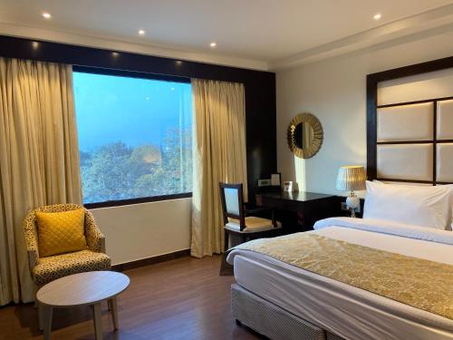 a hotel room with a bed and a desk and a window at Fortune Park, Haridwar - Member ITC's Hotel Group in Haridwār