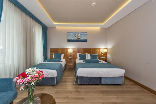 a hotel room with two beds and a vase of flowers at The Meretto Hotel Istanbul Old City in Istanbul